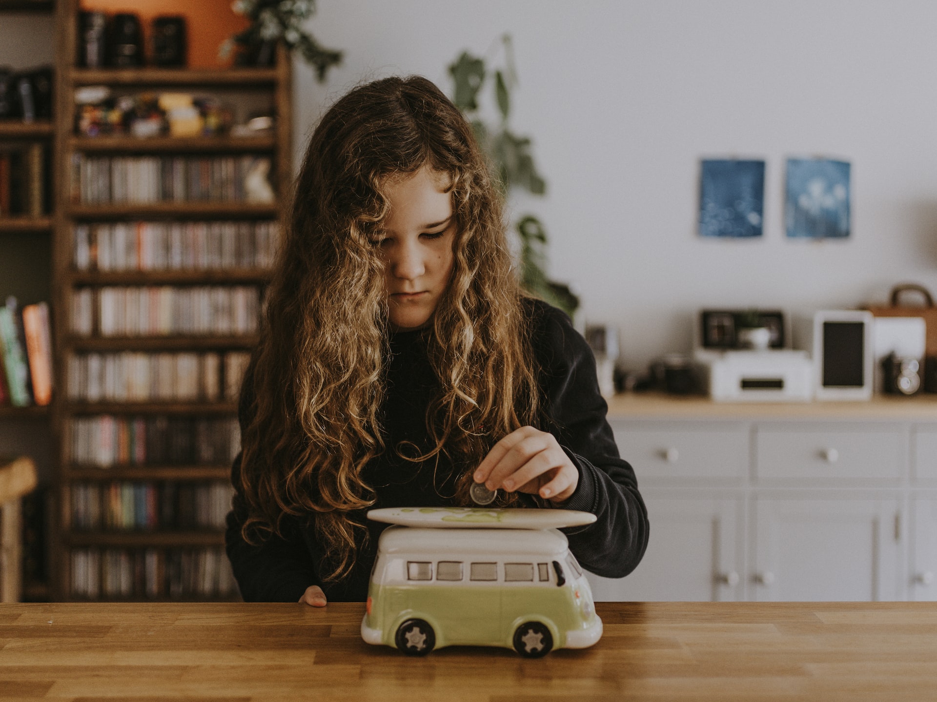 Ein junges Mädchen spielt mit der Attrappe eines Busses auf einem Holztisch.