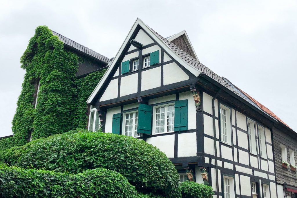 Fachwerkhaus mit grünen Fensterläden und belaubter Fassade