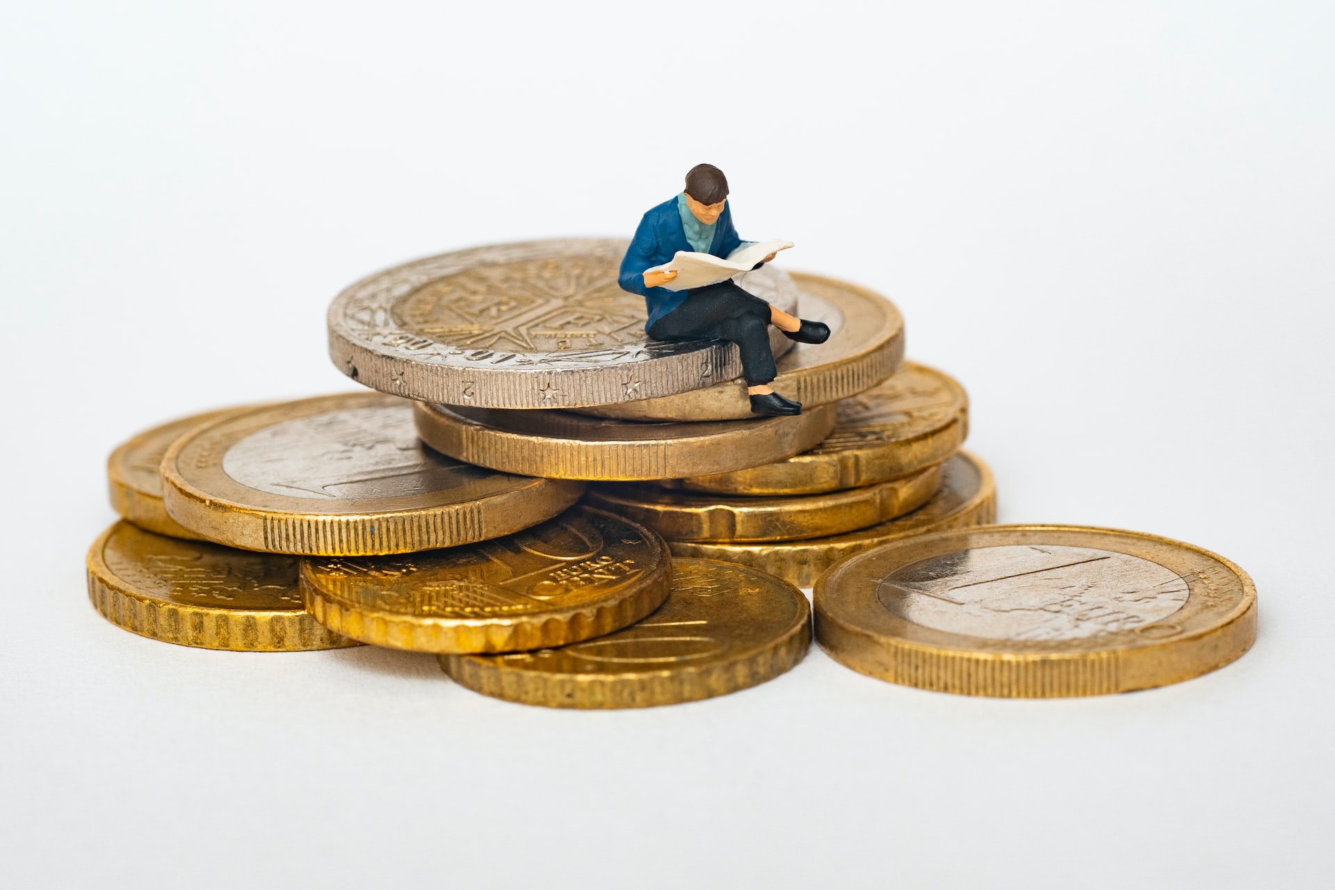 Kleiner Mann sitz auf einem Stapel münzen