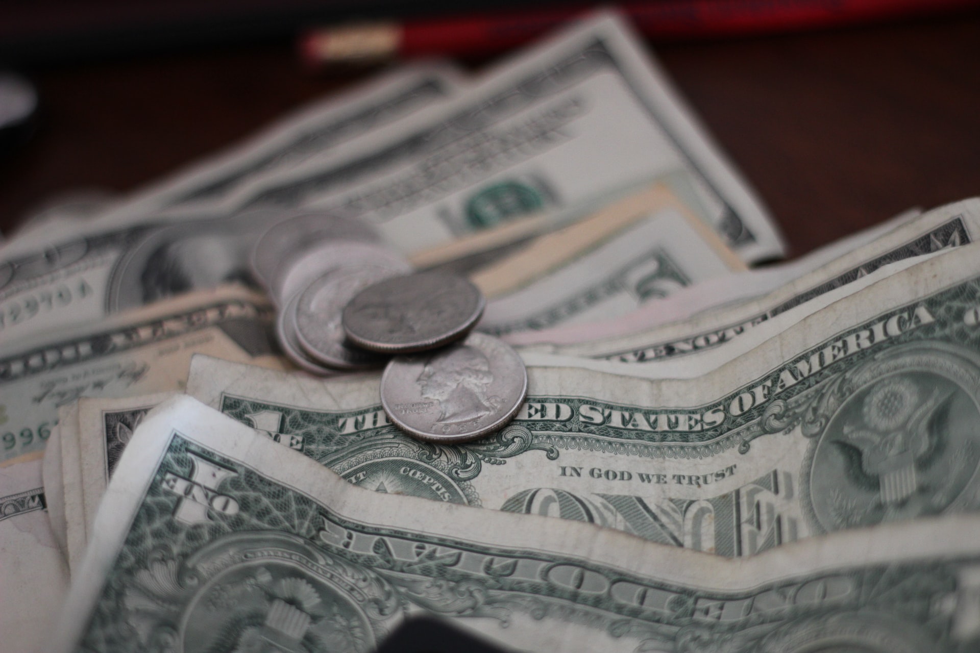 Ein-Dollar-Scheine und ein paar Münzen, die auf einem Bürotisch verteilt sind