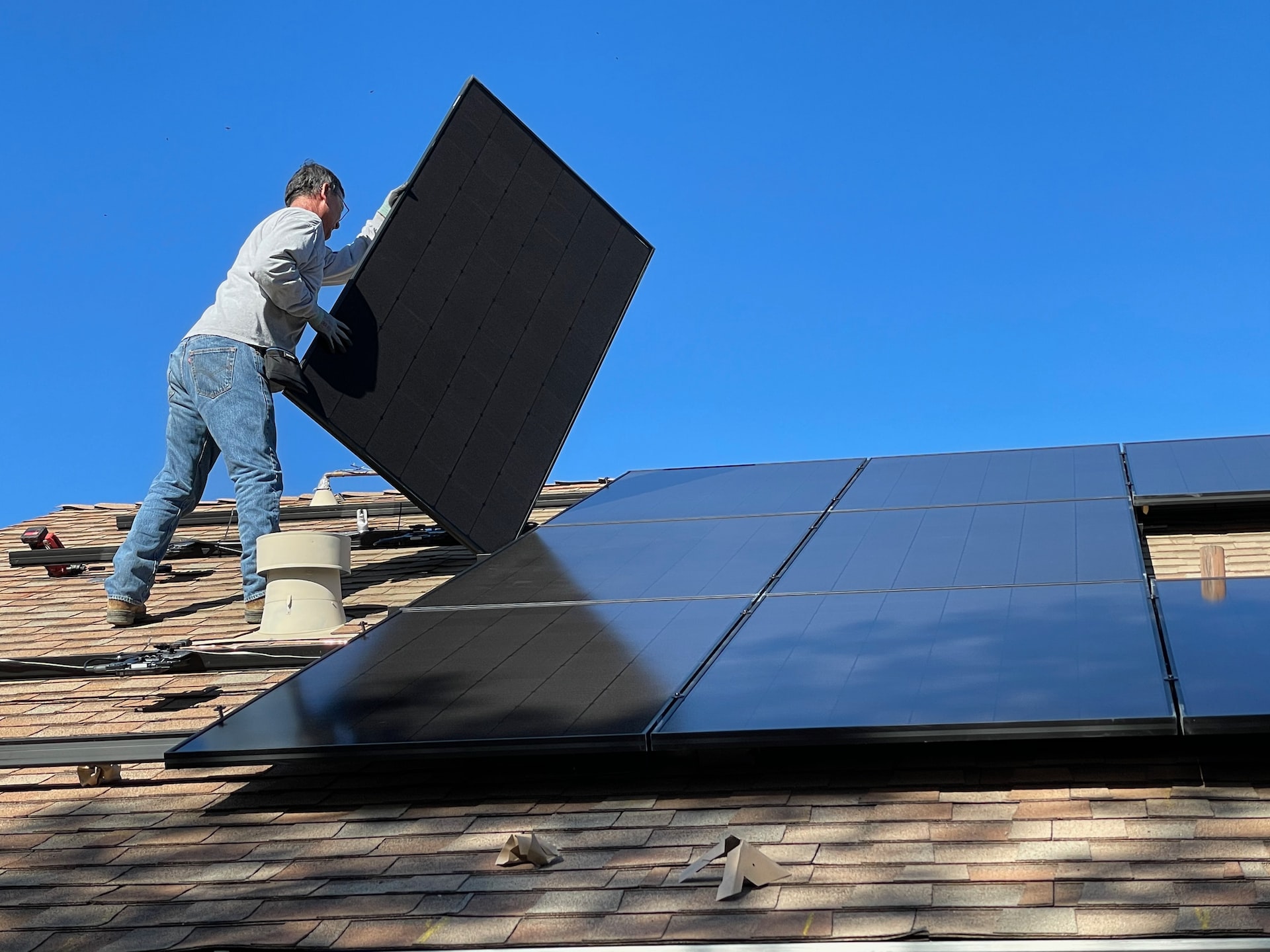 Ein Mann verlegt Solarzellen auf einem Dach