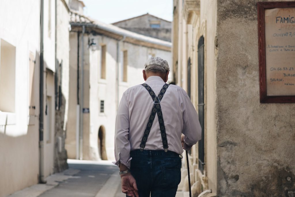 Alter Mann läuft eine Straße entlang