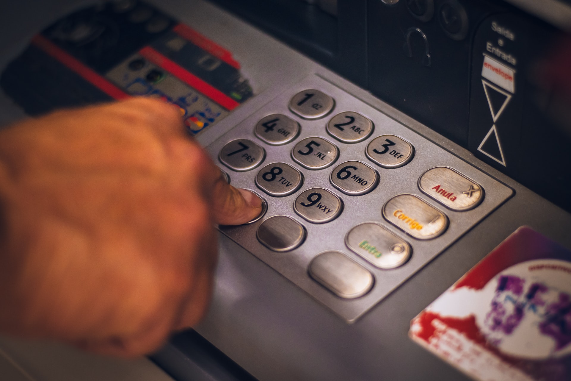 Eine Hand tippt eine PIN an einem Bankautomaten ein