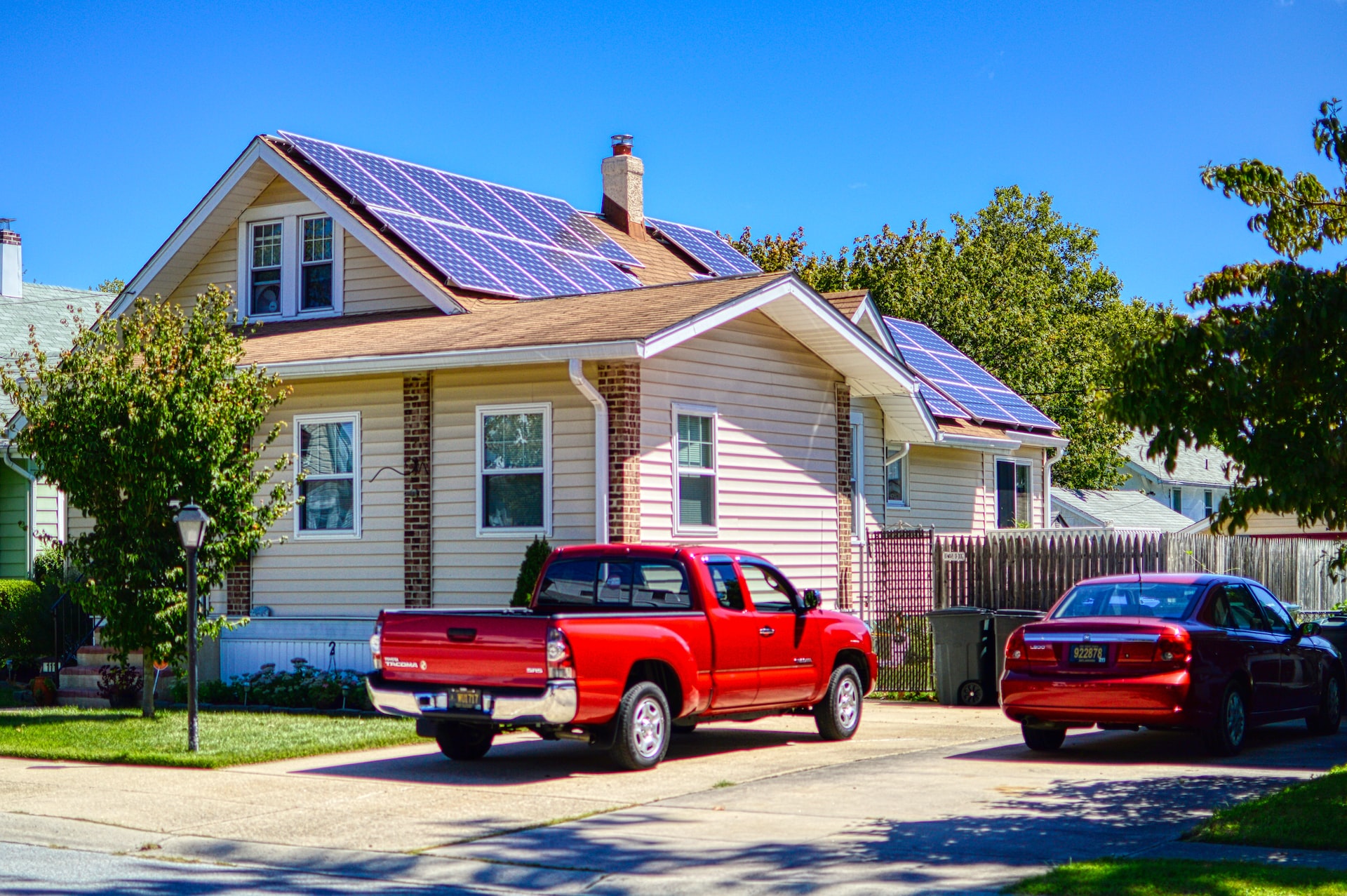 Einfamilienhaus mit Sonnenkollektoren und roten Autos vor dem Haus