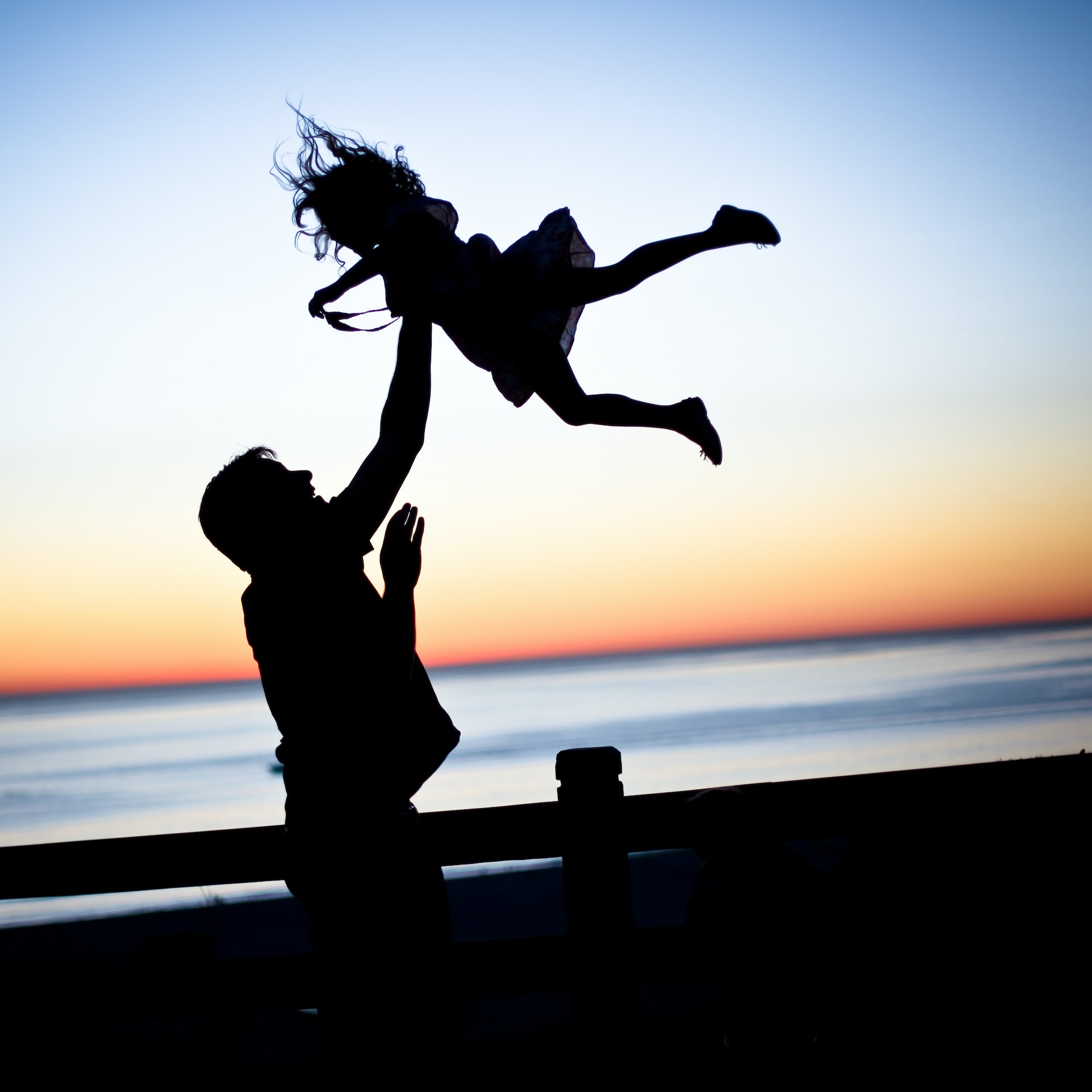 Mädchen und Vater spielen am Strand im Sonnenuntergang