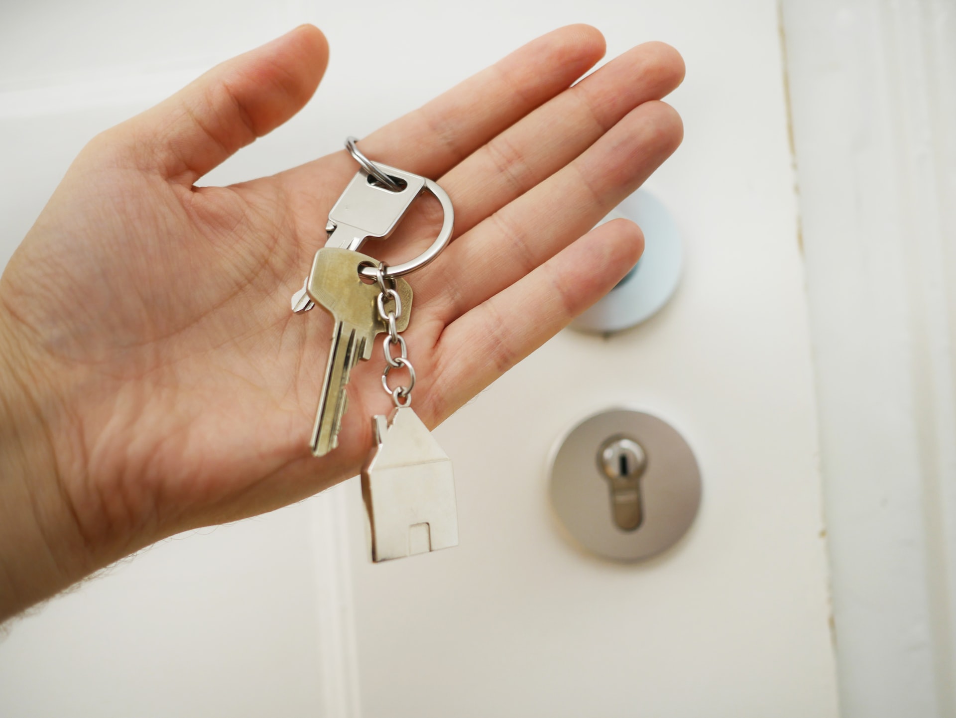 Schlüssel mit Hausschlüsselanhänger in einer Hand