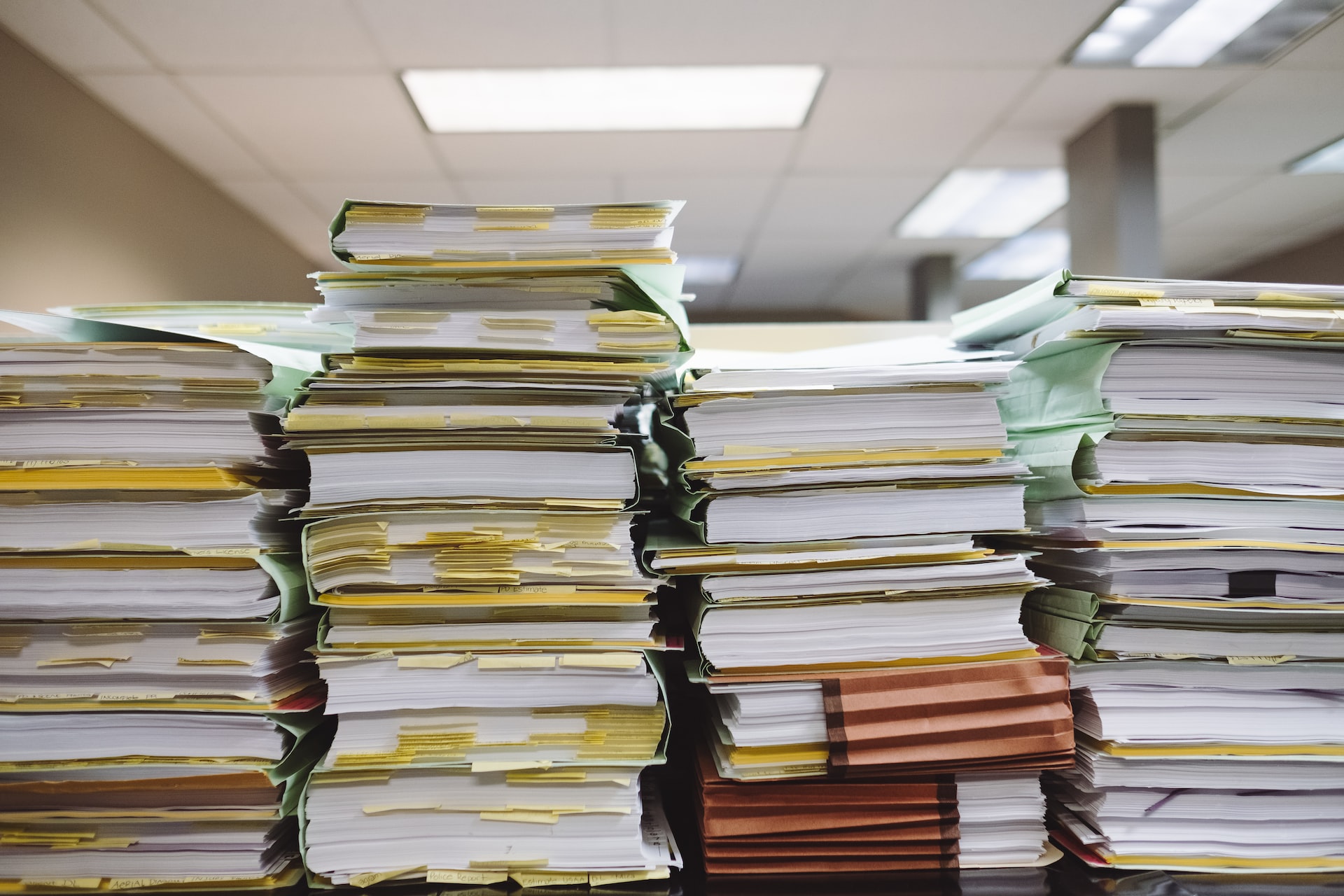 Vier große Stapel von Papierkram und Dokumenten auf einem Tisch in einem Büro