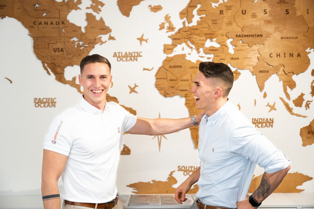 Jürgen und Matthias Nussbaumer posieren vor einer Weltkarte